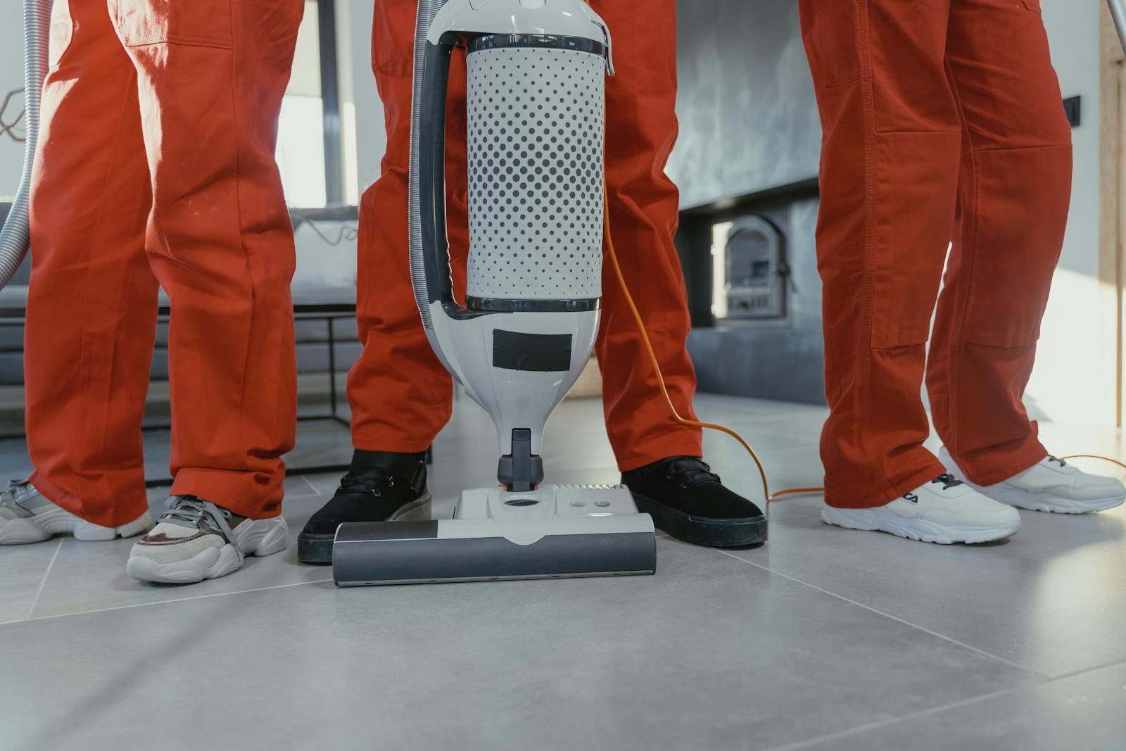 Limpieza Abella Orteguerira Coruña Team of professional cleaners in red uniforms using a vacuum cleaner indoors.